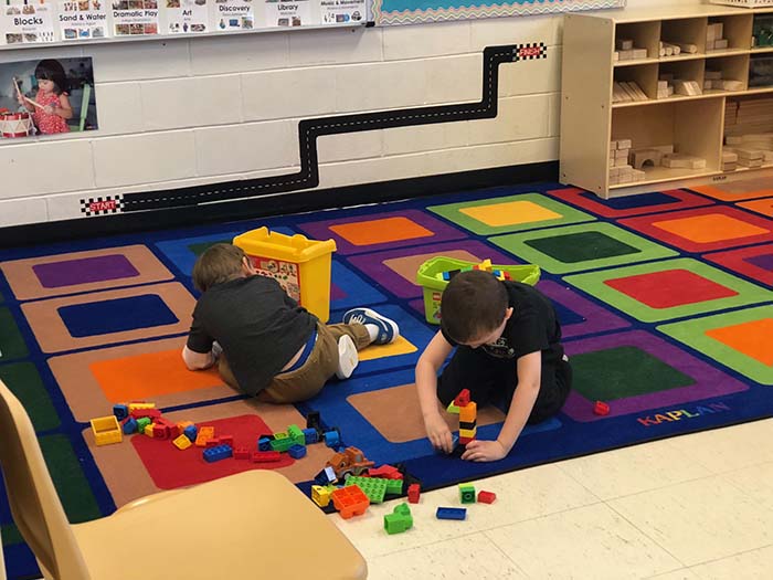 Two preschool students are focused on creating with building blocks before heading into nap time. (Photo by Kimberly Bosco)