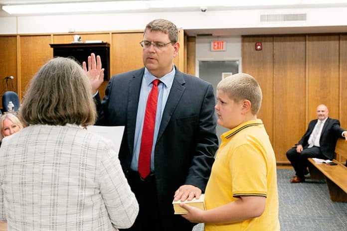 Robert Hudak, with his son Michael holding the family Bible, was sworn in as councilman by clerk Marie Key on May 28. (Photo by Jennifer Peacock)